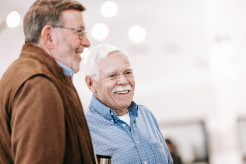 Two older men smiling together at an event