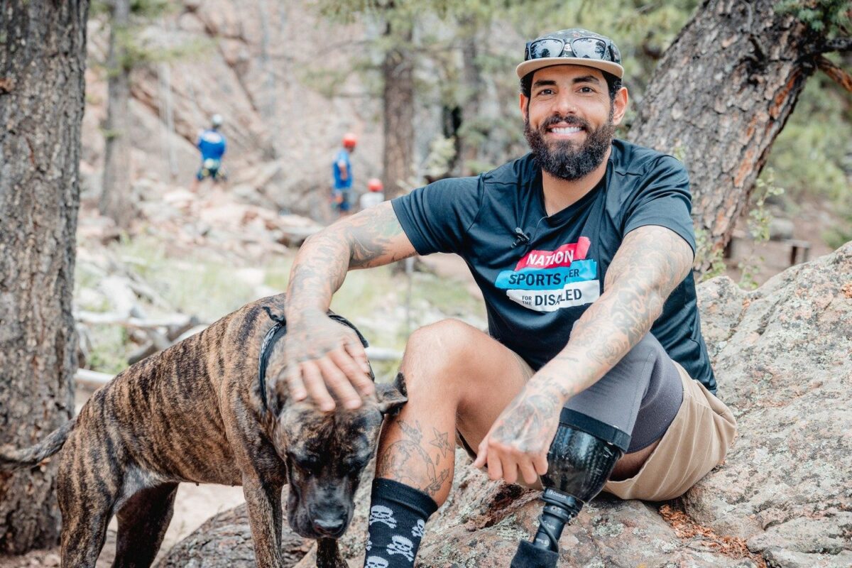 Cris, an NSCD participant and volunteer, sitting at the base of a climb with his dog