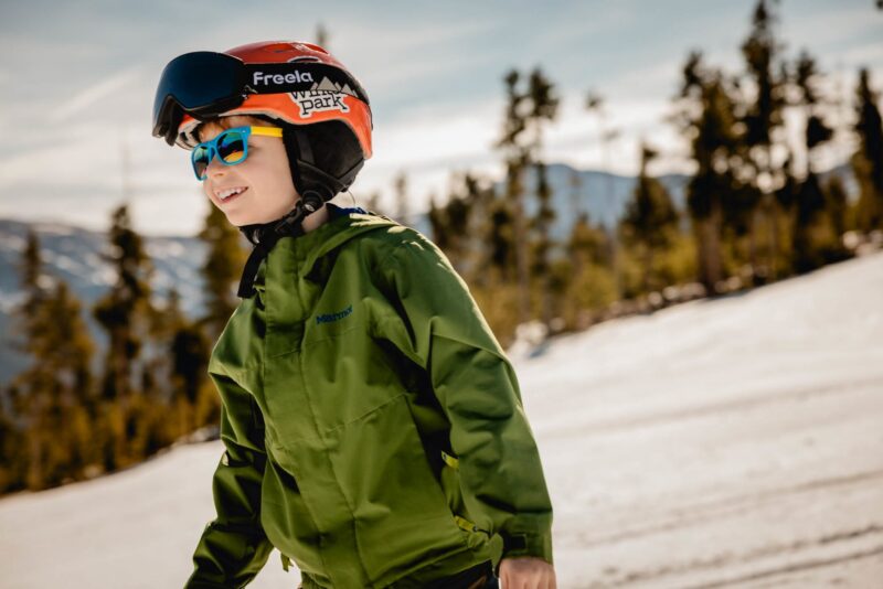 A young skier in a green jacket during an NSCD ski lesson